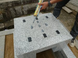 免震効果のある黒いゴム状のシートを使って石を積み上げます。