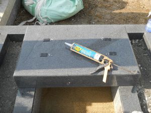 地震対策として、揺れを軽減する黒いゴム状のシートと耐震ボンドで大切なお墓をお守りしています。